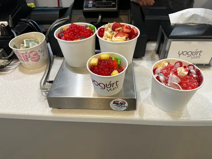 Four cups of frozen yogurt loaded with fruit and popping boba